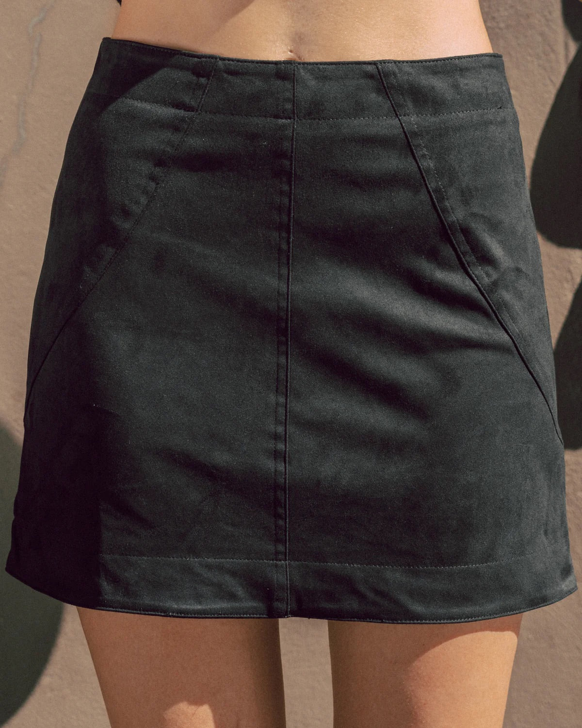 Black skirt worn by a person on a plain background