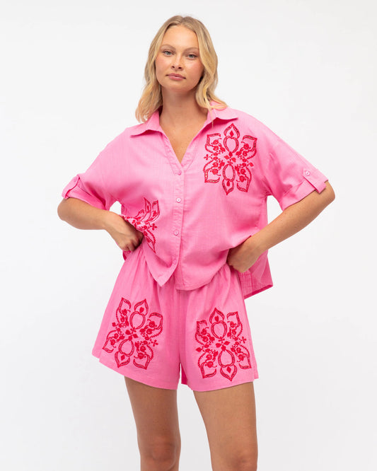 Woman wearing a pink outfit with floral patterns on a white background